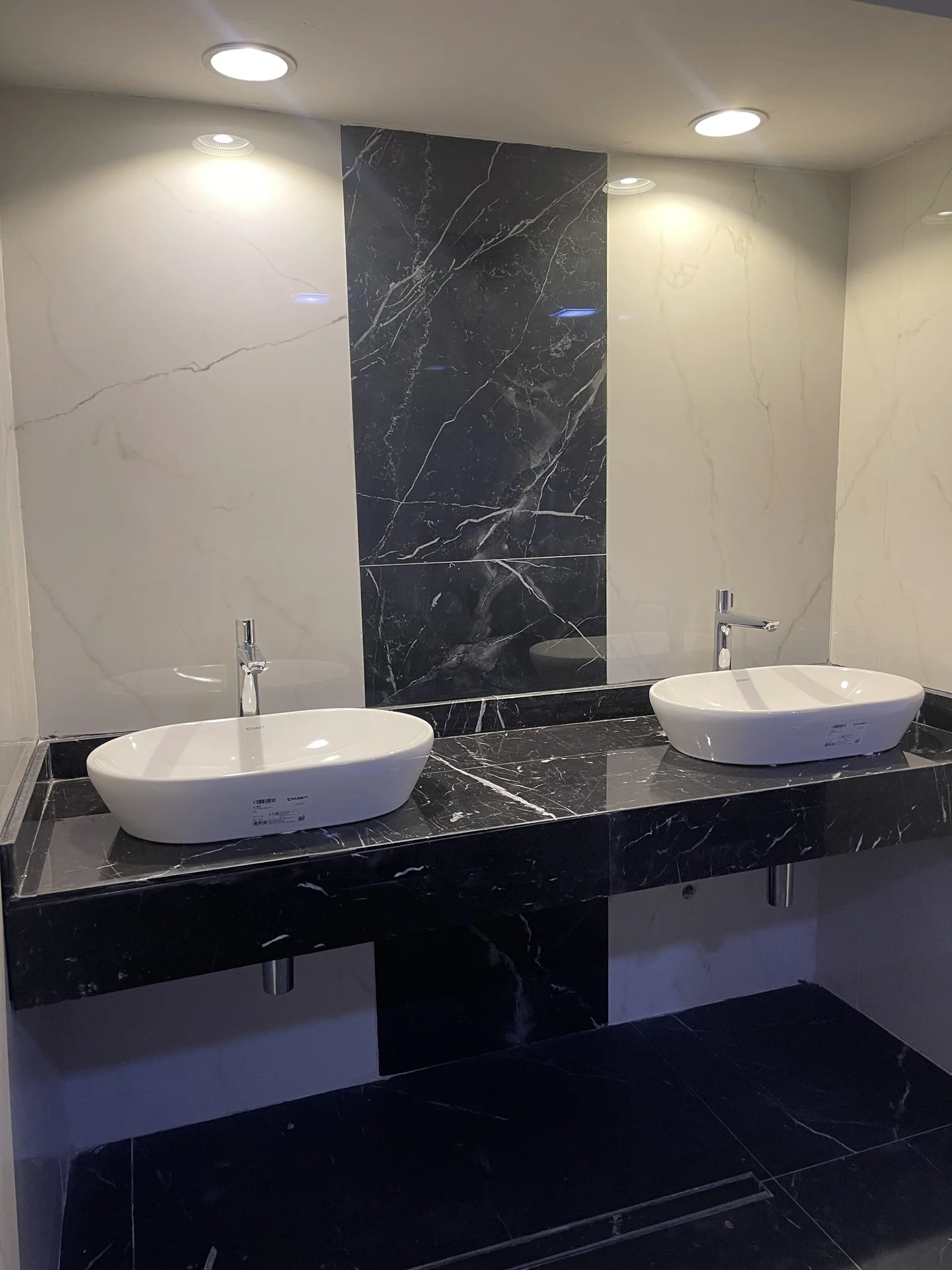 Stone-clad bathroom wall with twin vessel basins and concealed plumbing