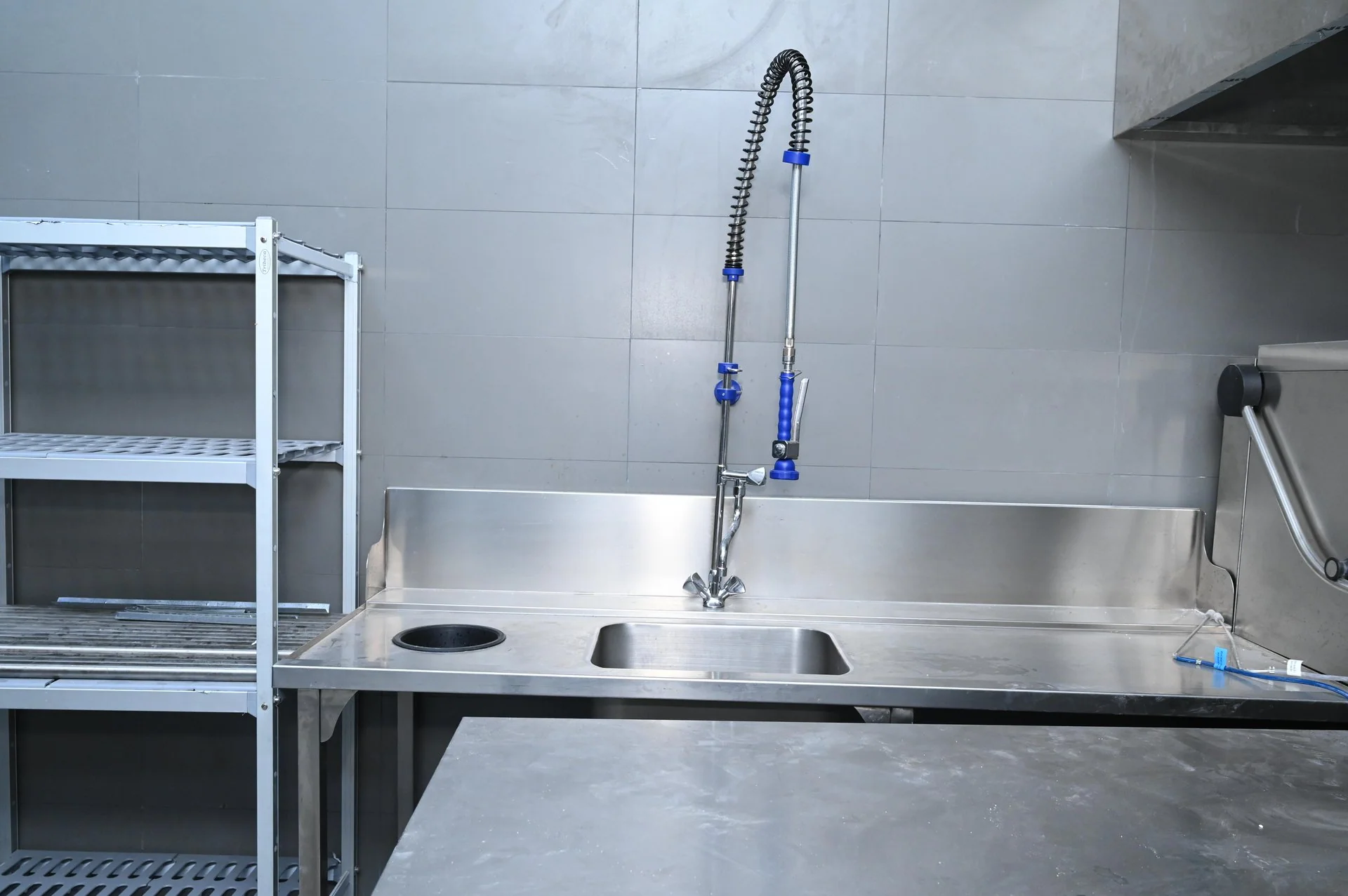 Commercial stainless-steel sinks and pre-rinse taps in a hotel kitchen